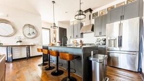 A modern kitchen with a central island, bar stools, stainless steel appliances, and wooden flooring. - Broadway Getaway-rooftop Patio-mins to The Gulch (Nashville)