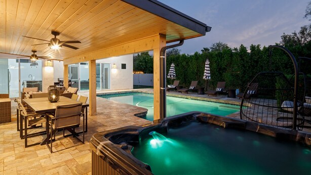 Un espace extérieur abrité comprenant un jacuzzi, des chaises longues et une piscine.