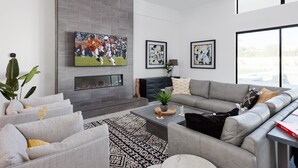 A modern living room with grey sofas, a fireplace, a flat-screen TV, and abstract art on the walls. - Luxe - Modern Mansion - Private Resort (Scottsdale)