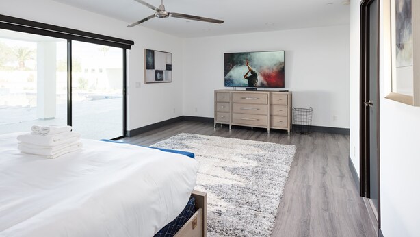 A modern bedroom with a bed, a ceiling fan, a TV, and a large window. - Luxe - Modern Mansion - Private Resort (Scottsdale)