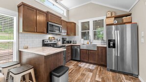 Une cuisine dotée de meubles en bois, d’appareils électroménagers en acier inoxydable et d’une fenêtre donnant sur un jardin.