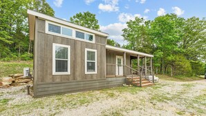 Une cabane moderne à deux étages, dotée d’un porche couvert et d’un mur en pierre.