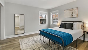 Een slaapkamer met een bed, een spiegel en een raam.