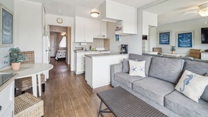 Een moderne keuken met witte kasten, een centraal eiland en een eethoek met rieten meubels.