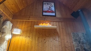 A cozy cabin interior with a wooden ceiling, a fireplace, a couch with fluffy cushions, and a magazine on the wall. - Tiny Cabin Couples escape! Hot tub, dry sauna, VIEWS!  (Gold Bar)