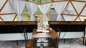 Un interior acogedor con una mesa de madera, dos bancos y vistas a través de un ventanal grande.