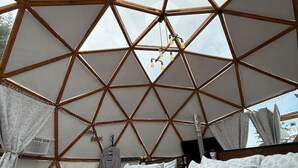 Una habitación con estructura geométrica en el techo, una cama con almohadas y una lámpara colgante.