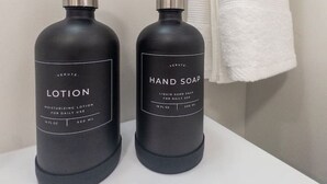 Twee zwarte flesjes lotion en handzeep op een wit oppervlak.