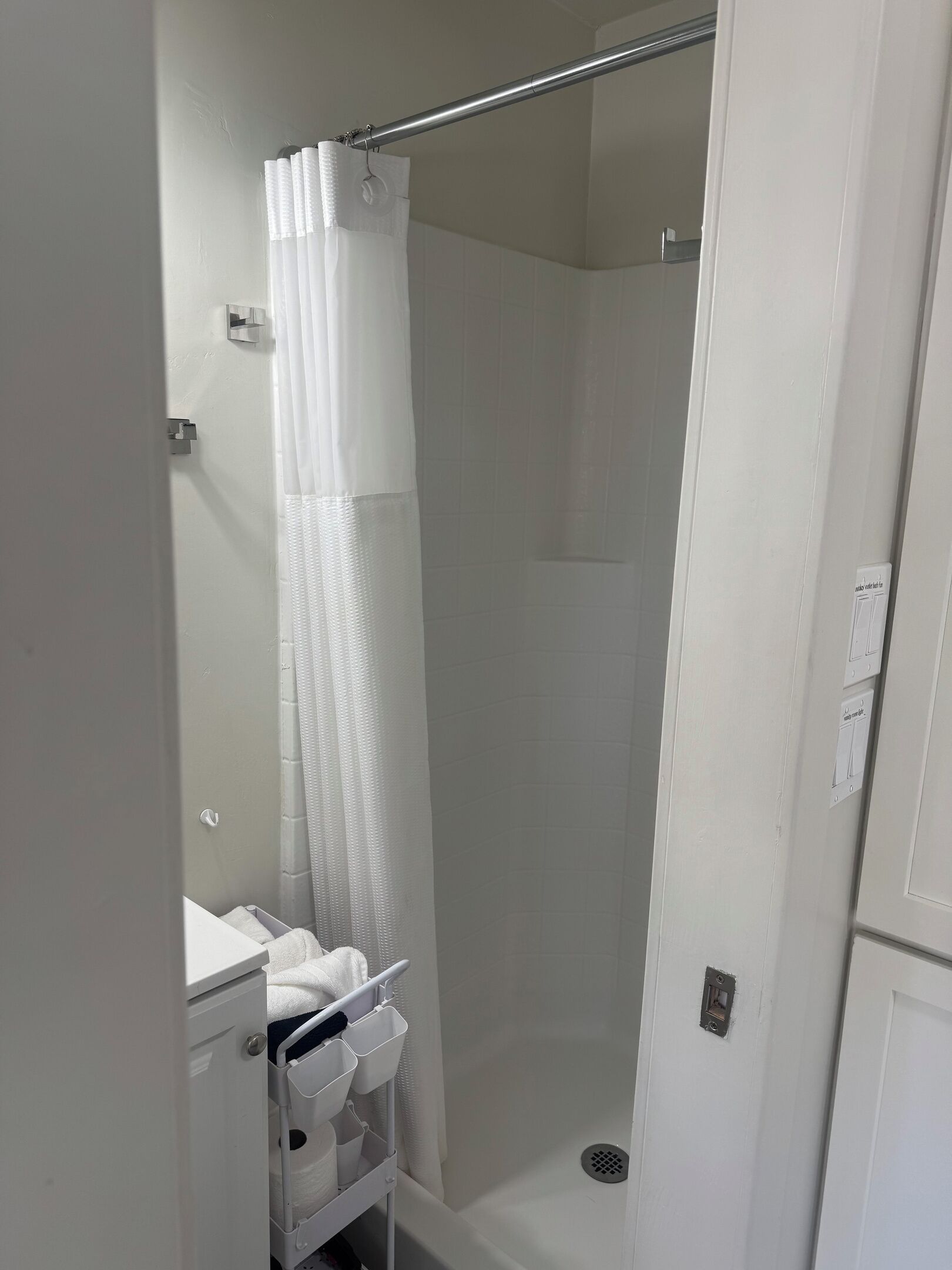 Een witte badkamer met douche, toilet en wastafel.