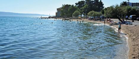 A beach with clear water, a pier, and people enjoying the area.
