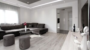 A modern living room with a sectional sofa, a round coffee table, and a grey ottoman. - Gorgeous apartment in Kastel Kambelovac (Kastel Kambelovac)