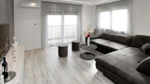 A modern living room with a grey sofa, a round coffee table, and a dining area with a wooden table and chairs. - Gorgeous apartment in Kastel Kambelovac (Kastel Kambelovac)