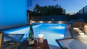 A poolside setting with a table, two glasses, a bottle of wine, and a lit candle. - Gorgeous apartment in Kastel Kambelovac (Kastel Kambelovac)