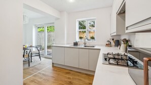 A modern kitchen with white cabinets, a gas stove, and a window. - Veitch Gardens - Perfect Spot to explore Exeter (Devon)