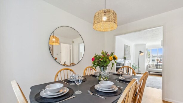 A dining area with a round table set for four, a mirror, and a hanging light fixture. - Veitch Gardens - Perfect Spot to explore Exeter (Devon)