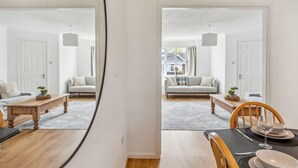 A modern living room with a sofa, coffee table, and dining table set up. - Veitch Gardens - Perfect Spot to explore Exeter (Devon)