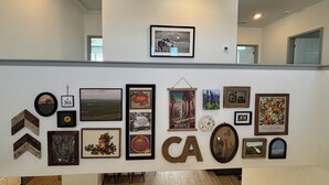 Un mur orné de divers tableaux encadrés et sur lequel figure un grand panneau avec les lettres « CA ».