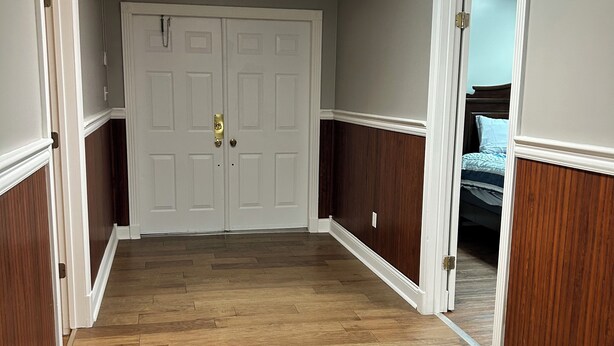 A hallway with wooden flooring, white doors, and a ceiling light fixture.
