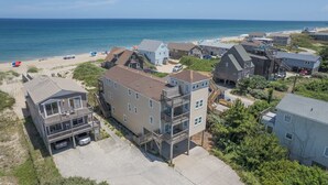 A coastal residential area with multiple two-story houses, a beach, and a clear view of the ocean. - 5770- What A View - Oceanfront Getaway Near Jennette's Pier (Nags Head)
