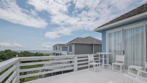 A balcony with white chairs and a view of the ocean. - 5593-Craven Haven, Nags Head OBX Retreat | Pool & Sunset Views (Nags Head)