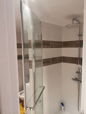 Een douche, handdoeken, zeep, toiletpapier