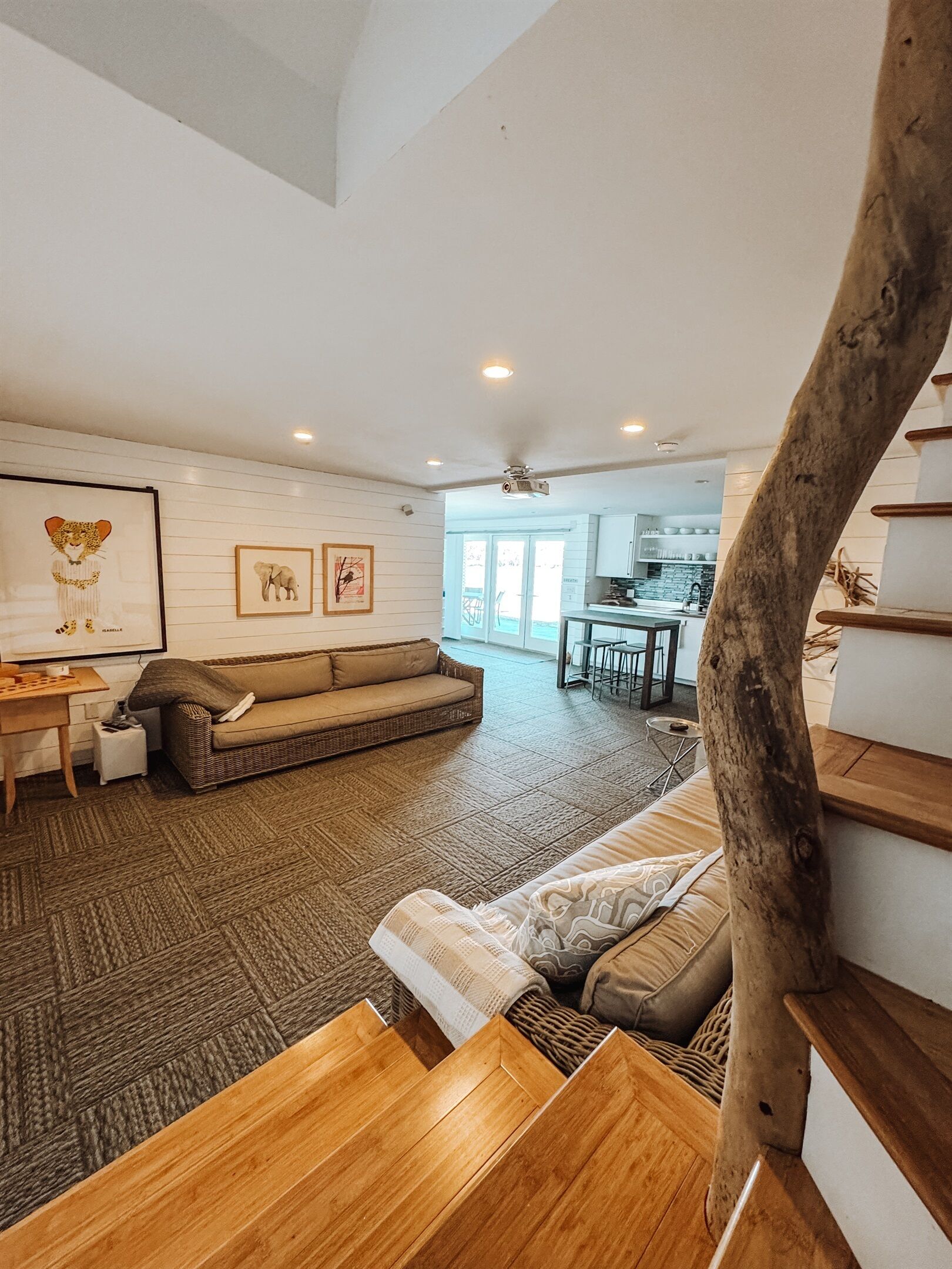 A spacious living area with a high ceiling, a wooden staircase, and a view into the kitchen.