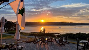 Une vue sur le coucher de soleil depuis une terrasse avec des sièges d’extérieur et un drapeau.