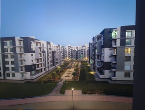 Um complexo de apartamentos moderno com vários edifícios, varandas e um pátio bem cuidado.