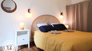 A bedroom with a bed, bedside lamps, a nightstand, a mirror, and a curtain. - Gîtes de France® - Le Clo (SAINT MICHEL DE BANNIERES)