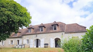 A stone building with multiple windows and shutters, a grassy yard, and a large tree. - Gîtes de France® - Le Clo (SAINT MICHEL DE BANNIERES)