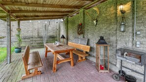 An outdoor patio with a wooden table and benches, a lantern, and a stone wall.
