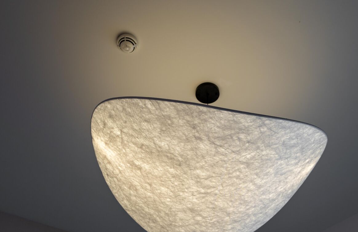 Un plafond agrémenté d’un luminaire texturé et de deux autres luminaires circulaires encastrés.
