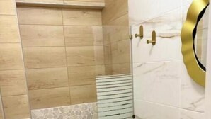 Un baño con inodoro, lavamanos y cabina de ducha.