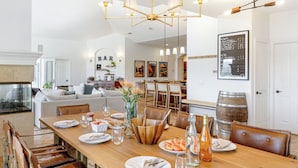 A dining area with a wooden table, chairs, and a chandelier. There is a bar area in the background with a sign that reads 'BAR'. - Pool, Views, Hot Tub, Fire Pit & Arcade Vista Clara by Avantstay (Temecula)
