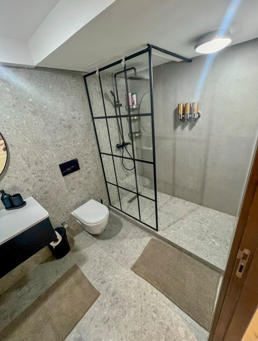 Ein modernes Badezimmer mit einer gläsernen Duschkabine, einer Toilette und einem Waschbecken mit Spiegel.