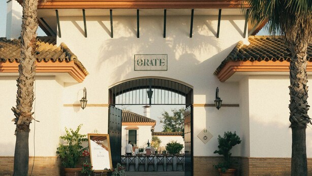 A building with a sign reading "ORATE" above a gated entrance.
