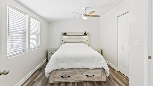 A bedroom with a bed, a ceiling fan, a nightstand, and a door. - Waterbury Way - Quiet family retreat with patio! (Russells Point)