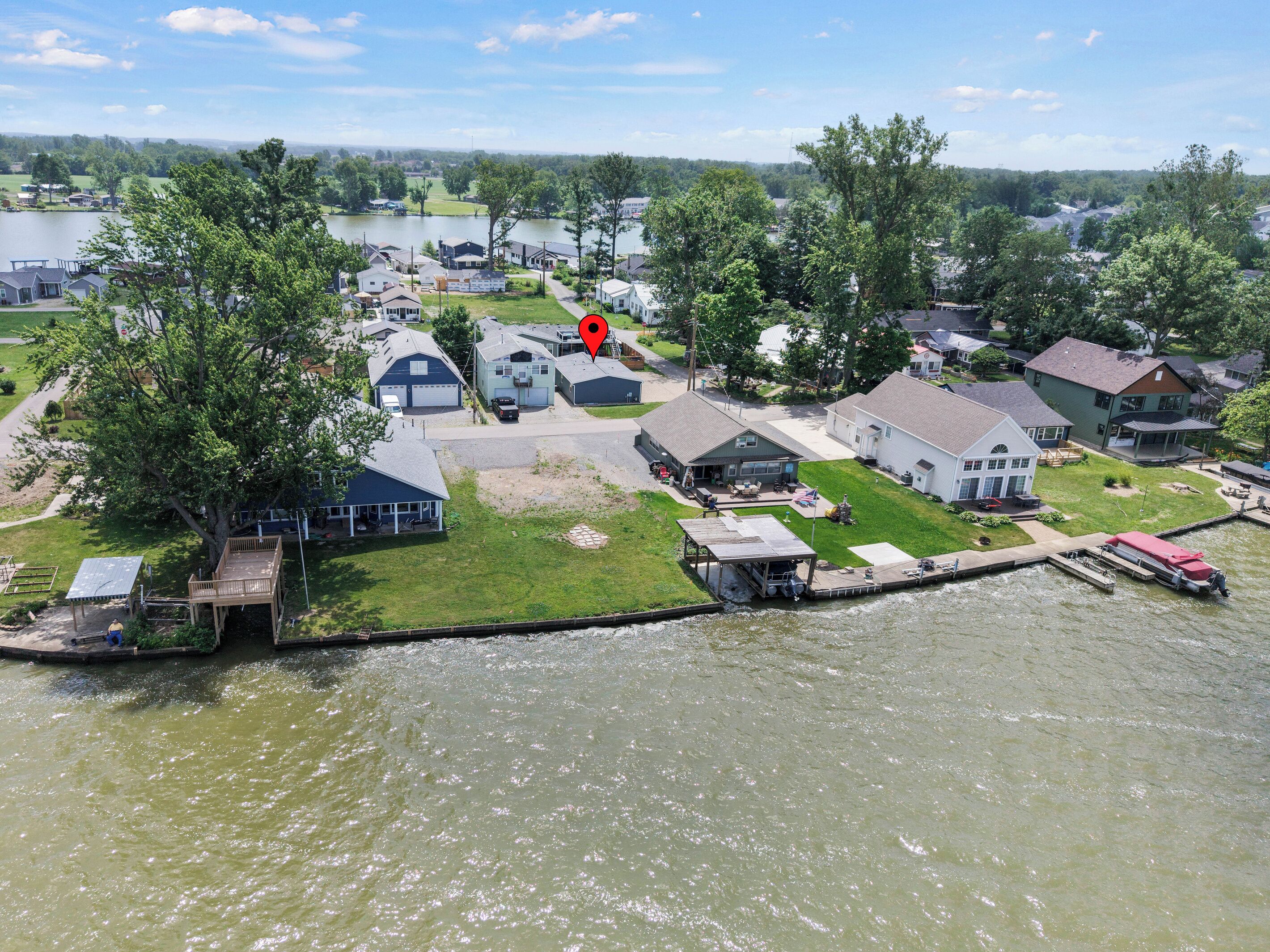 Un barrio residencial junto al lago, con casas, un muelle y un bote.