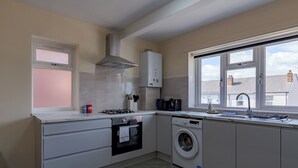A modern kitchen with a built-in oven, microwave, and washing machine, large windows, and a view of the neighborhood. - Modern Cozy 2BR- Private Parking- Near WBA (Birmingham)