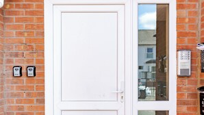 A white double door with a small window, a mailbox, and a doorbell on a brick wall. - Modern Cozy 2BR- Private Parking- Near WBA (Birmingham)