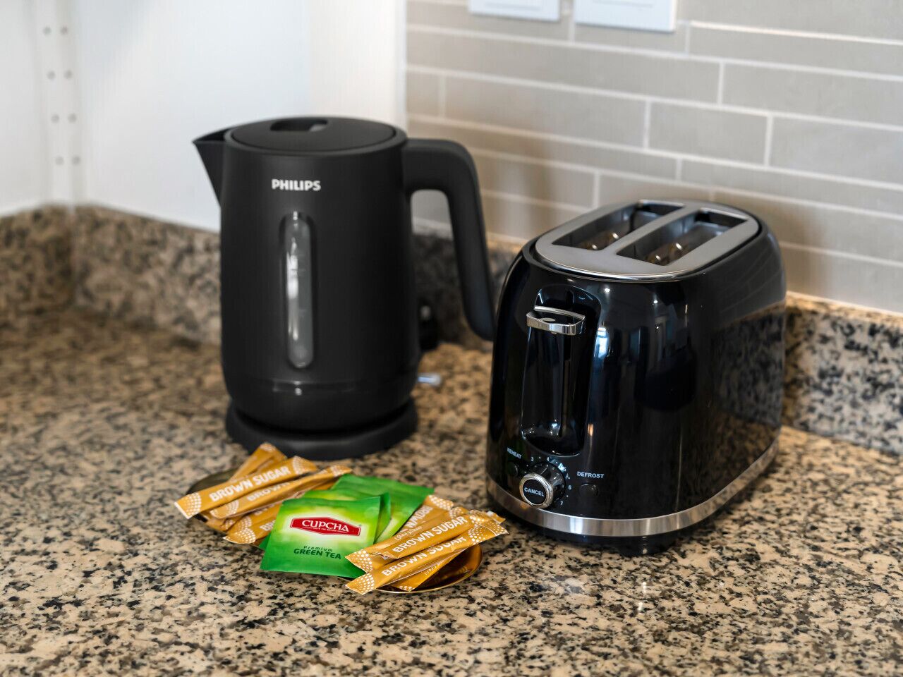 A kitchen counter with a Philips coffee maker, a toaster, and packets of tea and snacks.