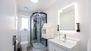 A modern bathroom with a glass-enclosed shower, a white sink, and a large mirror.