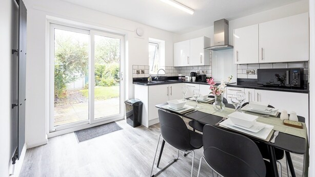 A modern kitchen with white cabinets, a black countertop, and a dining area with a table set for two.