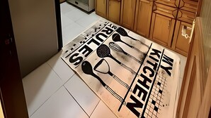 Een moderne keuken met een gasfornuis, houten kastjes, een spoelbak en een decoratieve mat op de vloer.