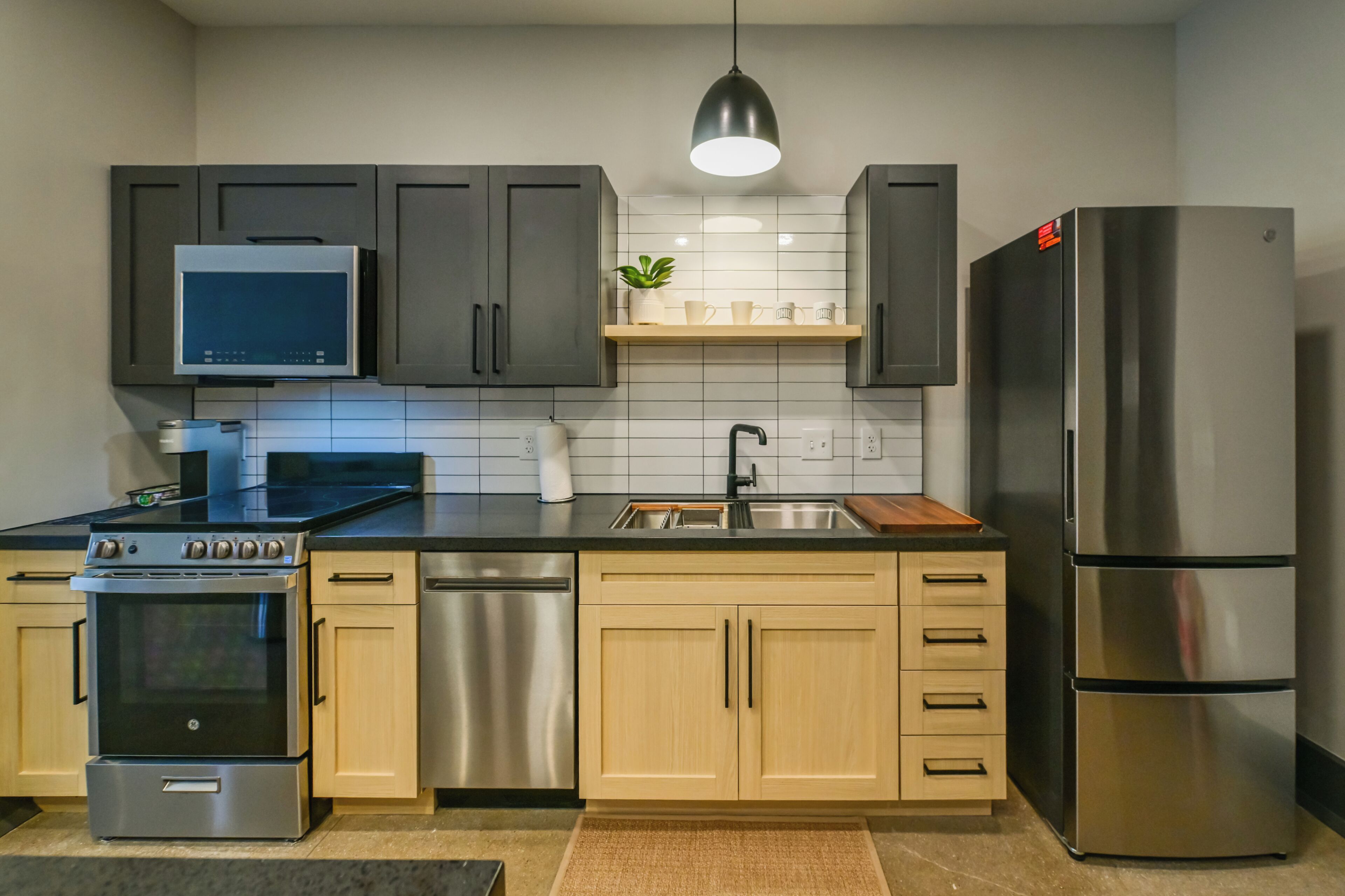 Une cuisine moderne dotée d’appareils électroménagers en acier inoxydable, de meubles en bois et d’un four à micro-ondes encastré.