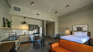 Une chambre d’hôtel moderne dotée d’une kitchenette, d’un coin repas et d’un grand lit.