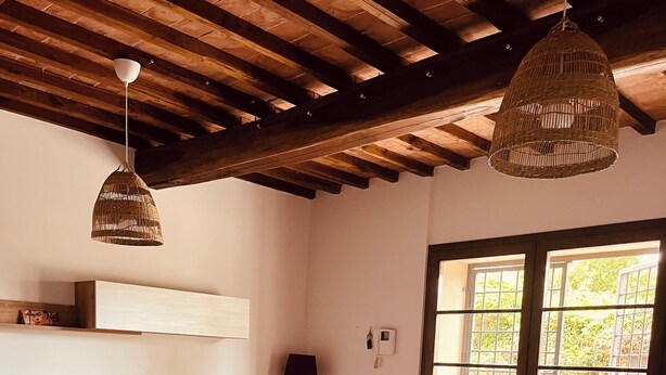 Una habitación acogedora con un sofá, una mesa de madera y una lámpara colgante.