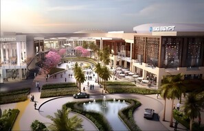 Un centre comercial modern amb una font central, palmeres i un cinema.