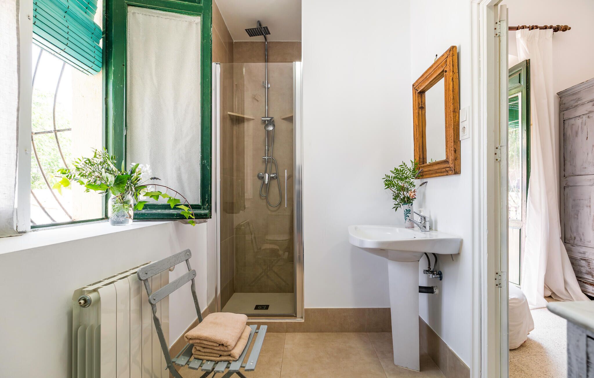 A bathroom with a shower, a sink, a mirror, and a radiator.