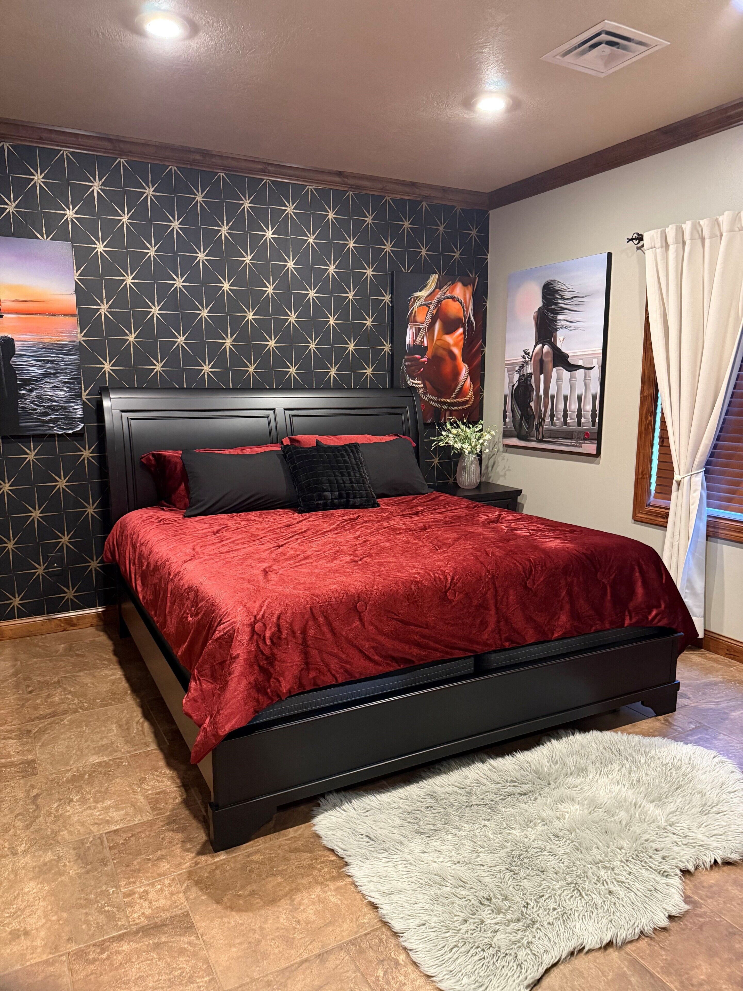 A bedroom with a large bed, a patterned wall, and artwork.